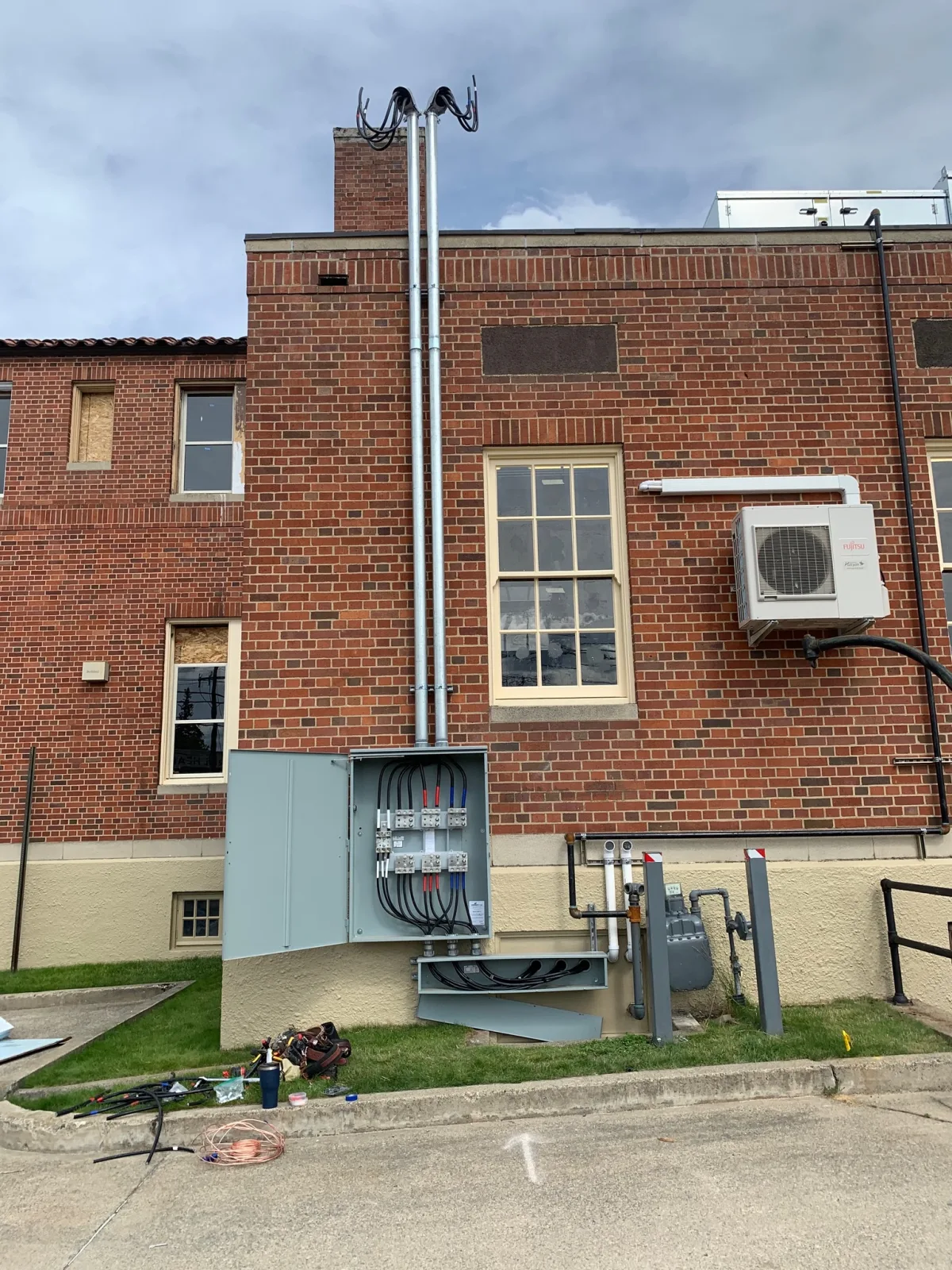 New service entrance with meter, disconnect panel, conduit mast riser, and a mini-split on the brick wall